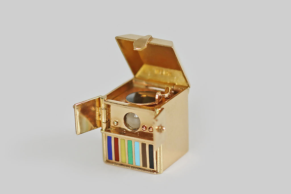Antique Jewelry Portland, Vintage Jewelry Portland , Antique Engagement Rings | A rare and wonderful, complex, mid 20th century charm, modeled as a record player, in 14k yellow gold. This miniature record player is housed an old-school cabinet, whose dust cover and small, front-facing doors all open and close! It is complete with a tiny gold arm, a glossy black enamel record, and a series of cheerful, rainbow-colored bars