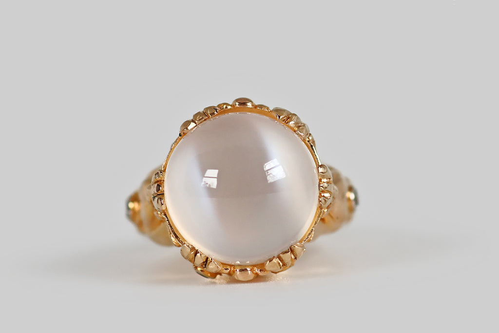 Poor Mouchette | Curated Antique Jewelry, Vintage Jewelry & Engagement Rings | A big, soulful, 1970s cocktail ring, modeled in 18k yellow gold, that features a magical, round cat's eye moonstone cabochon! This glowing white moonstone is held in six clusters of triple-prongs, where it reads like a crystal ball, sitting atop a spiritualist's stand. The moonstone's two, striking, adularescent bands have a subtle blue flash, and these "eyes" shift across its high dome, with movement.