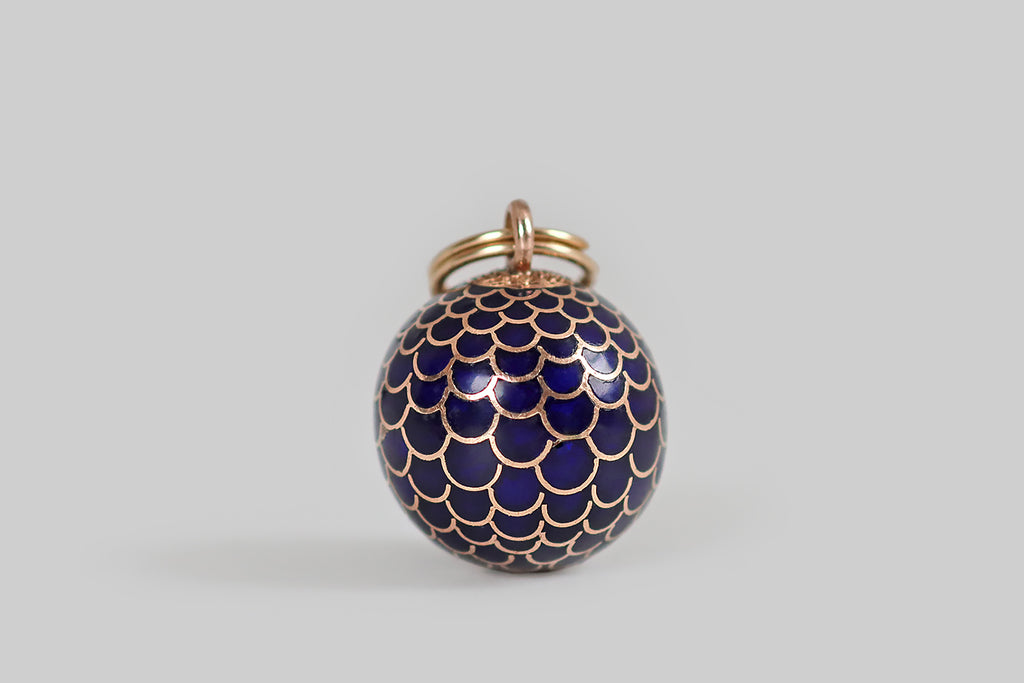Antique Jewelry Portland, Vintage Jewelry Portland , Antique Engagement Rings | Poor Mouchette | A beautiful, early 20th century charm, modeled in rosy 14k yellow gold and decorated with glassy cobalt blue enamel. This orb-shaped charm has an all-over pattern of scales (or feathers) that are largest at its center— the pattern of scales tightens at the orb's poles. This scaled look