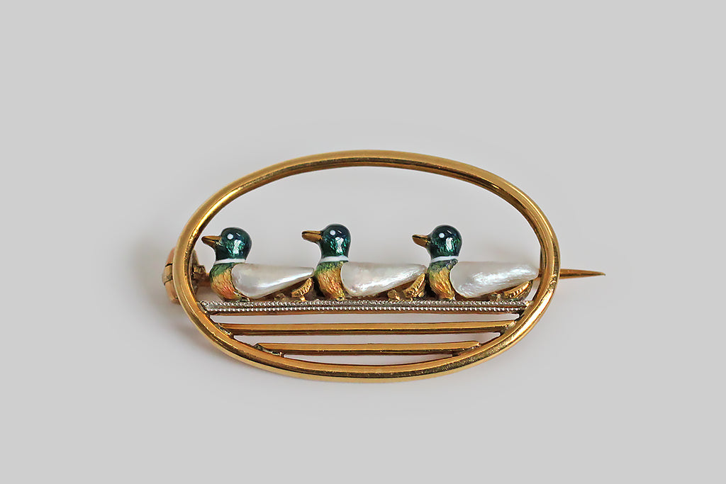 Poor Mouchette | Curated Antique Jewelry, Vintage Jewelry & Engagement Rings | Portland, Oregon | An Edwardian era pearl and enamel brooch, modeled in 18k yellow gold and platinum, depicting a trio of duck friends, inside an oval frame. These three mallards float together along a milgrained platinum wire. They are finely embellished with translucent, multicolored enamel, and each duck's wing is a tiny, white, Mississippi river pearl!