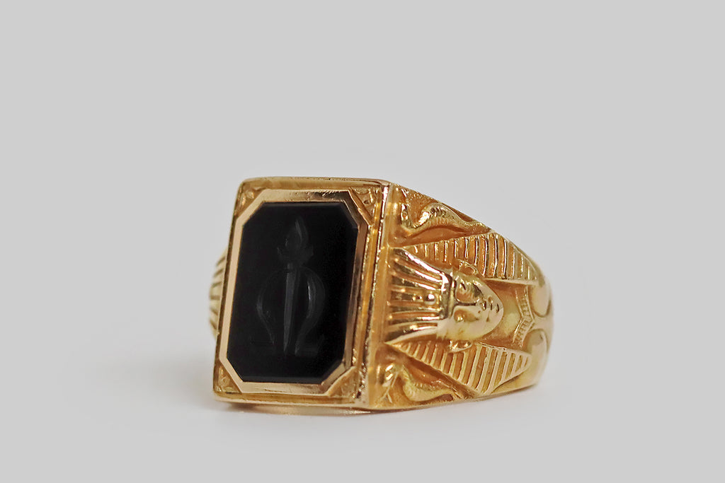 Poor Mouchette | Curated Antique Jewelry, Vintage Jewelry & Engagement Rings | Portland, Oregon | An exceptional Art Deco era intaglio signet ring, modeled in 14k yellow gold, whose onyx seal is carved with a torch that intersects the greek letter omega (the end). This seal is held in an elaborate mount, whose finely-carved, figural decor has an Egyptian flavor⁠— the ring's broad shoulders both feature the bust of the pharaoh Hatshepsut