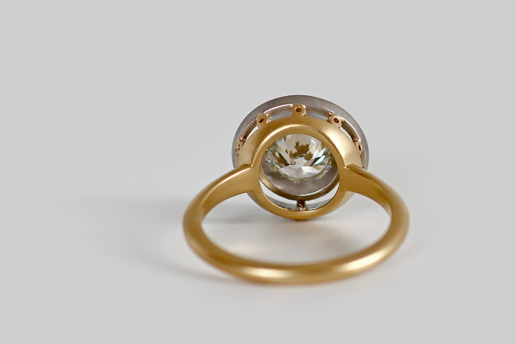 Poor Mouchette | Curated Antique Jewelry, Vintage Jewelry & Engagement Rings | Portland, Oregon | A newly hand-made engagement ring, whose gem in an antique, 1.25 carat Old European cut diamond (I/J, VS1). This brilliant old rainbow-maker is held in a smooth bezel, where (thanks to four small spacers) it appears to hover inside a second, larger bezel. Our target style ring face takes its inspiration from the delicate floating bezels of the Edwardian and Belle Epoque eras.