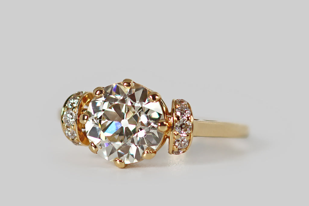 Poor Mouchette | Curated Antique Jewelry, Vintage Jewelry & Engagement Rings | Portland, Oregon | An elegant engagement ring, modeled in 18k yellow gold, whose primary gem is a striking 1.8 carat, old European cut diamond (GIA: L, SI1). This antique diamond is symmetrical and masterfully cut— it is held in eight prongs, atop the ring's crown-like basket, and its open culet reflects repeatedly in the stone's crown facets, creating a striking Kozibe effect!