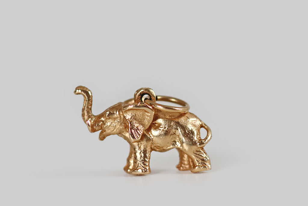Antique Jewelry Portland, Vintage Jewelry Portland , Antique Engagement Rings | Poor Mouchette | A sweet, miniature elephant charm, modeled realistically in 14k yellow gold, whose cheerful subject is depicted with a raised trunk. This lucky fellow is small but mighty— he is expressively carved and solidly cast, so he feels a bit like a gold nugget in wear. The lucky elephant concept originates in India and Southeast Asia