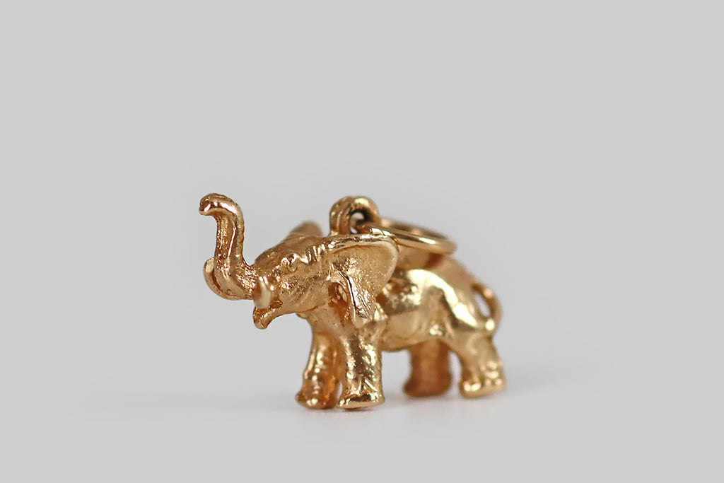 Antique Jewelry Portland, Vintage Jewelry Portland , Antique Engagement Rings | Poor Mouchette | A sweet, miniature elephant charm, modeled realistically in 14k yellow gold, whose cheerful subject is depicted with a raised trunk. This lucky fellow is small but mighty— he is expressively carved and solidly cast, so he feels a bit like a gold nugget in wear. The lucky elephant concept originates in India and Southeast Asia