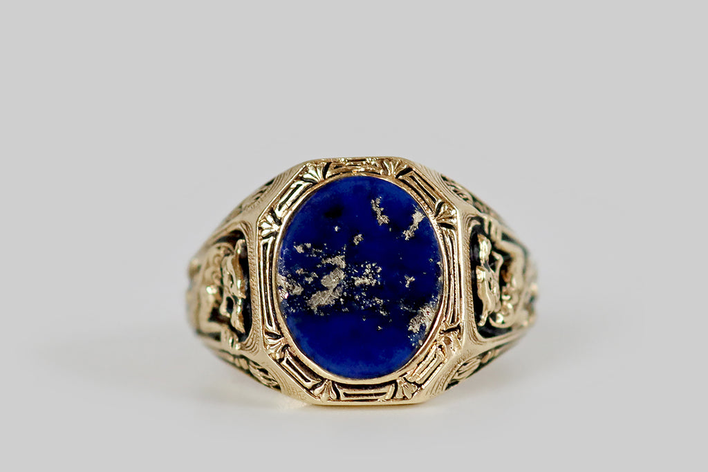 Antique Jewelry Portland, Vintage Jewelry Portland , Antique Engagement Rings | Poor Mouchette | A striking Art Deco era signet ring, modeled in 14k yellow gold, whose elongated, octagonal face is set with an oval slab of lapis lazuli. This bezel-set lapis gem is a rich, evenly-saturated, medium-blue color, and it is heavily figured with splashy, golden, pyrite inclusions! A border of pierced rectangles and fleur de lis surround it, while a pair of dragons flank it, adorning the ring's shoulders. 