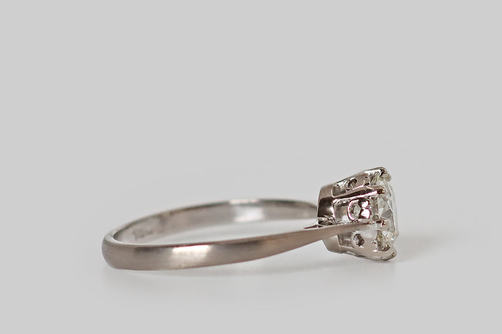 Antique Jewelry Portland, Vintage Jewelry Portland , Antique Engagement Rings | Poor Mouchette | An elegant 1940s engagement ring, modeled in 18k white gold, whose single gem is a vibrant 1.3 carat transitional cut diamond (H, SI1). This wonderful antique diamond sits in a crown-like basket, where it is held in place by eight prongs. The ring's shank is pinched at the shoulders, creating a lovely, delicate-looking "floating diamond"