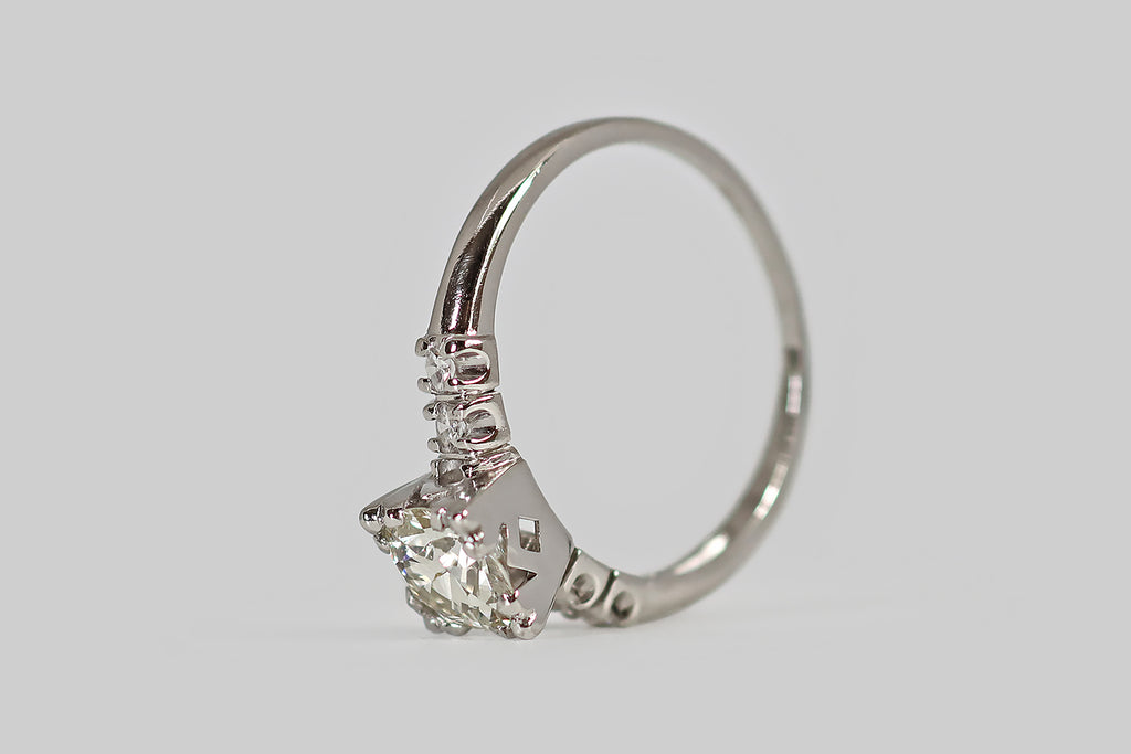 Antique Jewelry Portland, Vintage Jewelry Portland , Antique Engagement Rings | Poor Mouchette | A classic late Art Deco engagement ring, modeled in platinum, whose primary gem is a .87 carat old European cut diamond (G-H/VS1). This vibrant, hand cut diamond is mounted in a decoratively-pierced basket, where four, three-lobed, clover-like prongs hold it securely in place.