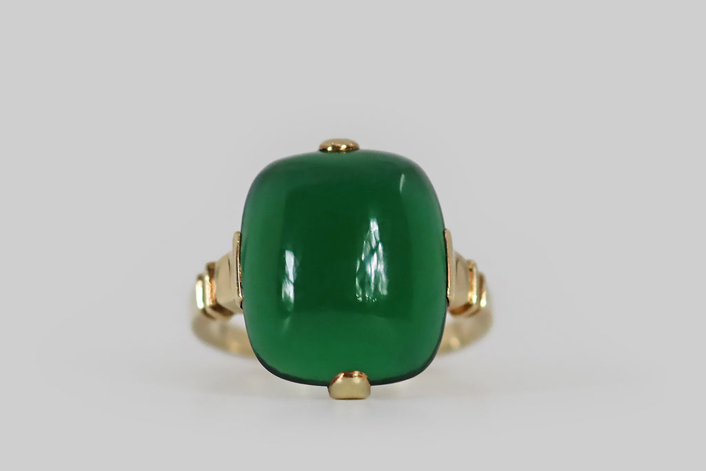 Antique Jewelry Portland, Vintage Jewelry Portland , Antique Engagement Rings | Poor Mouchette | A crisp, elegant, retro era ring, modeled in 14k yellow gold, featuring a gemmy, cushion-shaped, chrysoprase cabochon. This smooth, jade-green chrysoprase has a high dome and a soft square-round shape; it is held in four tab-style prongs atop an edgeless basket. The ring's shoulders are decoratively notched; its half-round shank has a square profile. 
