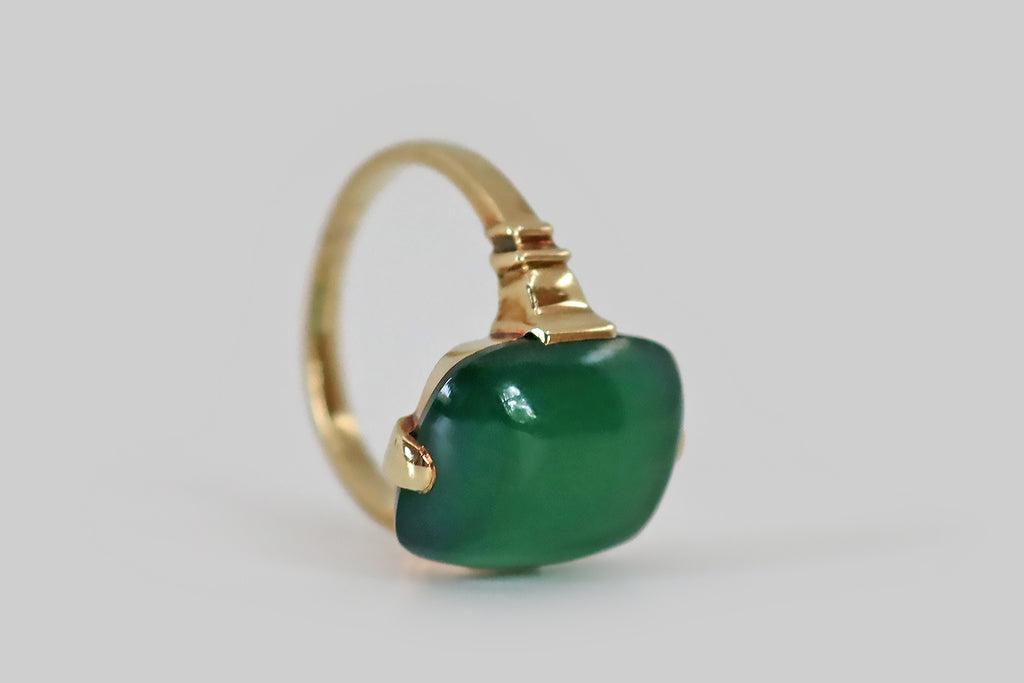 Antique Jewelry Portland, Vintage Jewelry Portland , Antique Engagement Rings | Poor Mouchette | A crisp, elegant, retro era ring, modeled in 14k yellow gold, featuring a gemmy, cushion-shaped, chrysoprase cabochon. This smooth, jade-green chrysoprase has a high dome and a soft square-round shape; it is held in four tab-style prongs atop an edgeless basket. The ring's shoulders are decoratively notched; its half-round shank has a square profile.