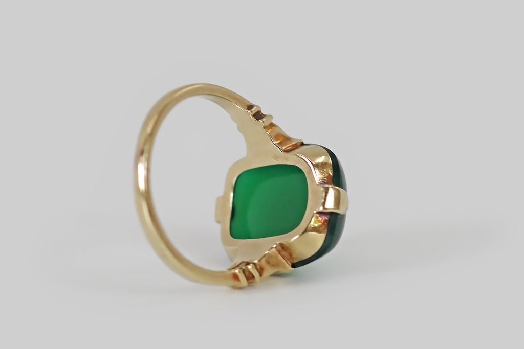 Antique Jewelry Portland, Vintage Jewelry Portland , Antique Engagement Rings | Poor Mouchette | A crisp, elegant, retro era ring, modeled in 14k yellow gold, featuring a gemmy, cushion-shaped, chrysoprase cabochon. This smooth, jade-green chrysoprase has a high dome and a soft square-round shape; it is held in four tab-style prongs atop an edgeless basket. The ring's shoulders are decoratively notched; its half-round shank has a square profile.