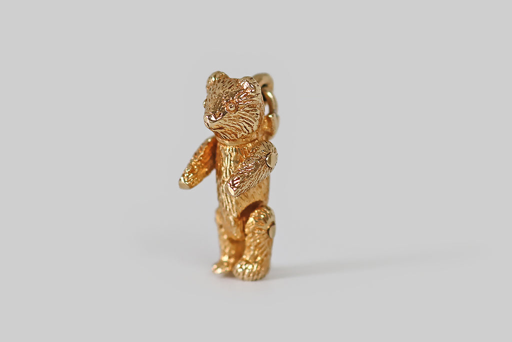 Antique Jewelry Portland, Vintage Jewelry Portland , Antique Engagement Rings | Poor Mouchette | A beautifully-made vintage charm, modeled as a miniature teddy bear, with jointed limbs, in 14k yellow gold. This little teddy is finely detailed, with "furry" texture. He wears a ribbon around his neck, that is tied into a floppy bow, at the back. His arms and legs are riveted and fully positionable.