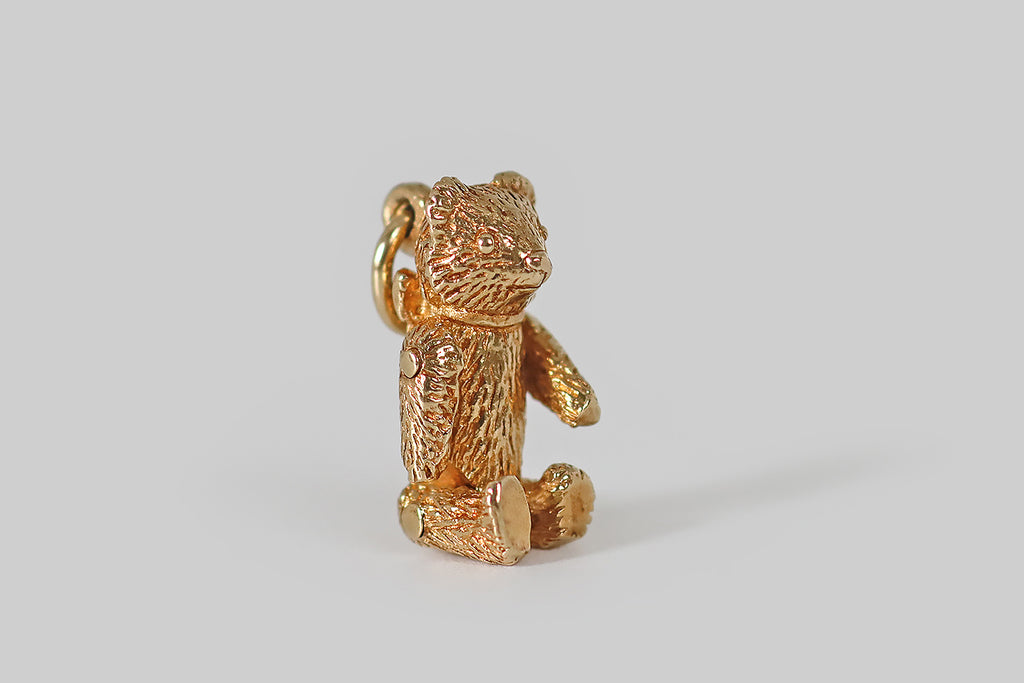 Antique Jewelry Portland, Vintage Jewelry Portland , Antique Engagement Rings | Poor Mouchette | A beautifully-made vintage charm, modeled as a miniature teddy bear, with jointed limbs, in 14k yellow gold. This little teddy is finely detailed, with "furry" texture. He wears a ribbon around his neck, that is tied into a floppy bow, at the back. His arms and legs are riveted and fully positionable.