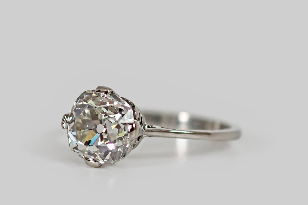 Antique Jewelry Portland, Vintage Jewelry Portland , Antique Engagement Rings | Poor Mouchette | An elegant, Art Deco era solitaire, modeled in platinum, whose gem is a striking 2.35 carat, old mine cut diamond (J/K, VS2). This rare, hand-cut diamond has a charming, slightly-irregular "square-round" shape, steep crown facets, and a small table. Looking through the diamond's table, the open culet and faceting-pattern create a subtle impression of flower petals, spread out around the culet.