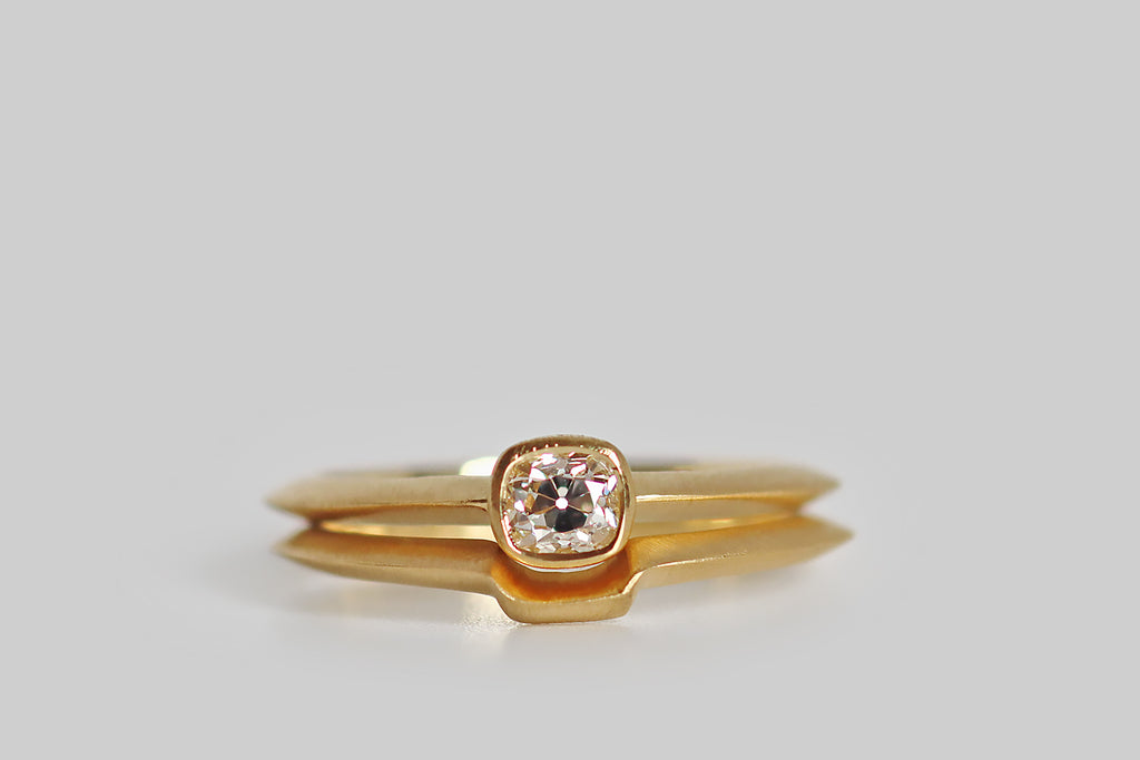 Poor Mouchette | Curated Antique Jewelry, Vintage Jewelry & Engagement Rings | Portland, Oregon | A low-profile, solitaire wedding set, modeled in 18k yellow gold, that features an antique .39 carat peruzzi cut diamond (J/VS). This charming antique diamond rests in a smooth bezel that is centered on the ring's dramatic knife-wire shank. The engagement ring is paired with a matching shadow band, that nests with it, perfectly following its lines. This set is both backward and forward looking.
