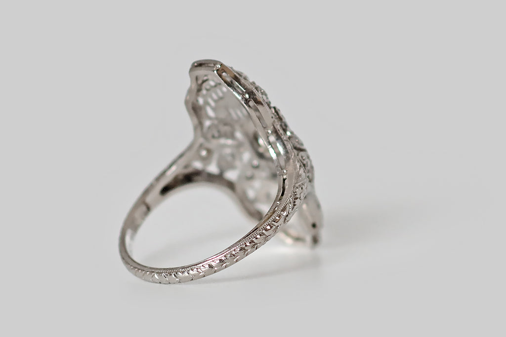 Antique Jewelry Portland, Vintage Jewelry Portland , Antique Engagement Rings | Poor Mouchette | A wonderful Art Deco era shield ring, modeled in platinum, whose artful filigree features four three-leaf clovers resting atop a field of delicate knife wire. The largest of these clovers are stationed to the north and south of the ring's primary diamond, bending gracefully to the right and to the left. This old European cut diamond is mounted in an octagonal seat