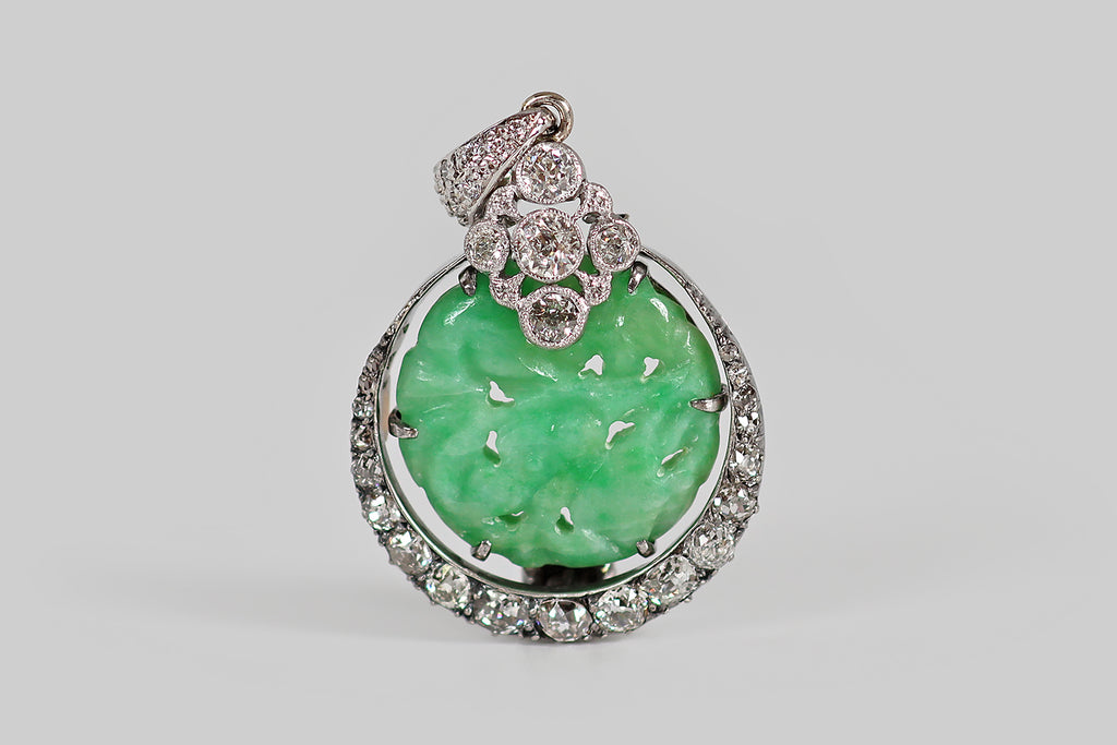 Poor Mouchette | Curated Antique Jewelry, Vintage Jewelry & Engagement Rings | A striking Art Deco era pendant, modeled in platinum, whose slender crescent moon cradles an apple-green jadeite jade disk. Our upturned crescent is set with 19 diamonds (four small rose cuts, and a graduating series of old mine cuts)— these are held in a pie crust channel, where they are supported by tiny bead-like prongs. The jade disc is hand-carved with an undulating floral pattern, and pierced. Crowning the jade disc