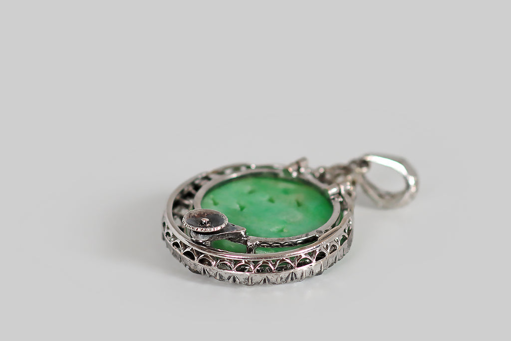 Poor Mouchette | Curated Antique Jewelry, Vintage Jewelry & Engagement Rings | A striking Art Deco era pendant, modeled in platinum, whose slender crescent moon cradles an apple-green jadeite jade disk. Our upturned crescent is set with 19 diamonds (four small rose cuts, and a graduating series of old mine cuts)— these are held in a pie crust channel, where they are supported by tiny bead-like prongs. The jade disc is hand-carved with an undulating floral pattern, and pierced. Crowning the jade disc