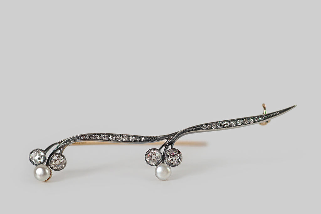Poor Mouchette | Curated Antique Jewelry, Vintage Jewelry & Engagement Rings | Portland, Oregon | An elegant, Art Nouveau era brooch, modeled in rosy 14k yellow gold with a silver top. This antique brooch takes the form of a graceful stem, with two nodding trefoil blossoms. The ribbon-like stems, here, are bead-set with small old mine cut diamonds that graduate toward the center. The trefoil blossoms are each composed of two larger, bezel-set, early old mine cut diamonds