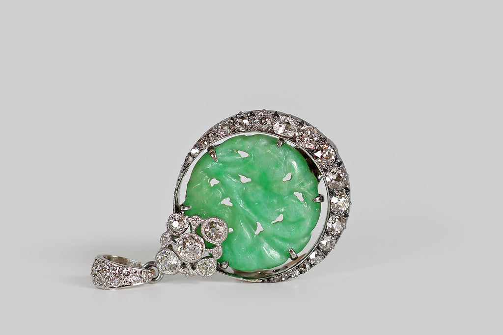 Poor Mouchette | Curated Antique Jewelry, Vintage Jewelry & Engagement Rings | A striking Art Deco era pendant, modeled in platinum, whose slender crescent moon cradles an apple-green jadeite jade disk. Our upturned crescent is set with 19 diamonds (four small rose cuts, and a graduating series of old mine cuts)— these are held in a pie crust channel, where they are supported by tiny bead-like prongs. The jade disc is hand-carved with an undulating floral pattern, and pierced. Crowning the jade disc