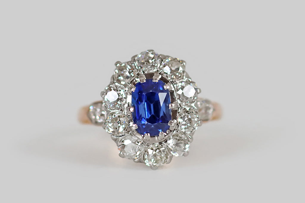 Poor Mouchette | Curated Antique Jewelry, Vintage Jewelry & Engagement Rings | A striking Edwardian-era cluster ring, modeled in 18k gold and platinum, whose primary gem is a bright, highly-saturated, 1.9 carat, no-heat Ceylon sapphire (GIA certified). This vibrant, old cushion-cut sapphire is mounted in ten prongs, and surrounded by a halo of ten, near-colorless, old European cut diamonds (H/I, SI). 