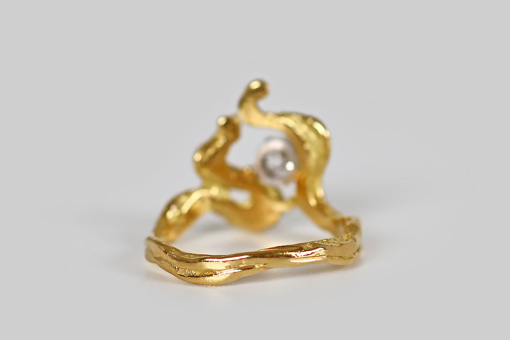Antique Jewelry Portland, Vintage Jewelry Portland , Antique Engagement Rings | Poor Mouchette | A striking, mid-twentieth-century ring, modeled in 18k yellow gold, whose irregular, curling form is suggestive of flames. These graceful, meandrous forms bend, curl, and rise to create the ring's sculptural face. A sparkling, round brilliant cut diamond rests off-center, in a four prong basket, where these curvaceous, flame-like lines lean together. We love this ring for its organic movement and its artfully 