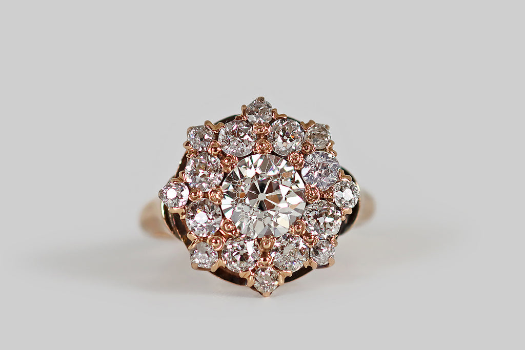 Poor Mouchette | Curated Antique Jewelry, Vintage Jewelry & Engagement Rings | A Victorian era cluster ring, modeled in rosy 14k yellow gold, whose primary gem is a .85 carat old European cut diamond (H, VS2). This central diamond is beautifully cut, with an open culet that reflects repeatedly in the stone's crown facets, creating a striking Kozibe effect! It is surrounded by a halo