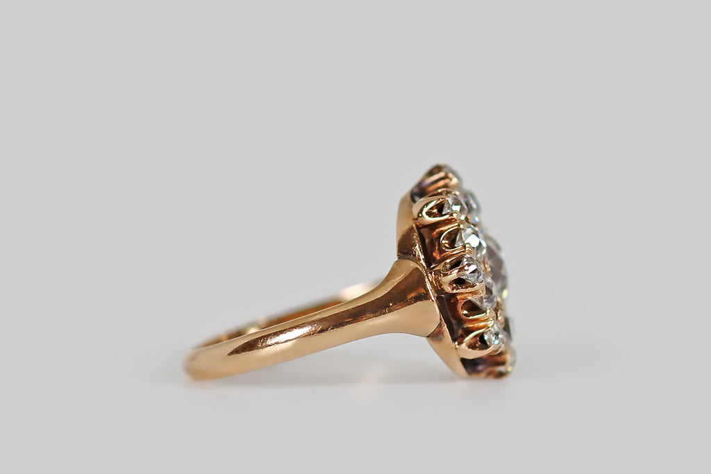 Poor Mouchette | Curated Antique Jewelry, Vintage Jewelry & Engagement Rings | A Victorian era cluster ring, modeled in rosy 14k yellow gold, whose primary gem is a .85 carat old European cut diamond (H, VS2). This central diamond is beautifully cut, with an open culet that reflects repeatedly in the stone's crown facets, creating a striking Kozibe effect! It is surrounded by a halo