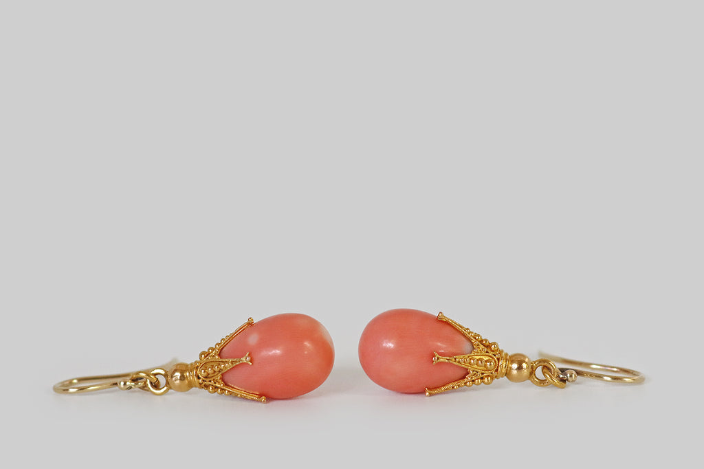 Poor Mouchette | Curated Antique Jewelry, Vintage Jewelry & Engagement Rings | Portland, Oregon | A pair of chubby, salmon-colored, natural coral teardrops, capped with ornate, five-claw mounts. These claws are extra-long and slender— they are decorated with fine twisted wirework and precisely-graduated balls of granulation. A gold ring connects these clawed toppers to a pair of handmade shepherd's hook ear wires.