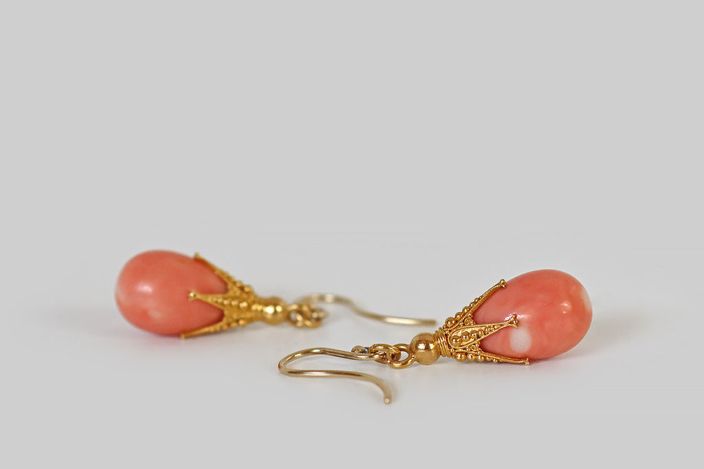 Poor Mouchette | Curated Antique Jewelry, Vintage Jewelry & Engagement Rings | Portland, Oregon | A pair of chubby, salmon-colored, natural coral teardrops, capped with ornate, five-claw mounts. These claws are extra-long and slender— they are decorated with fine twisted wirework and precisely-graduated balls of granulation. A gold ring connects these clawed toppers to a pair of handmade shepherd's hook ear wires.