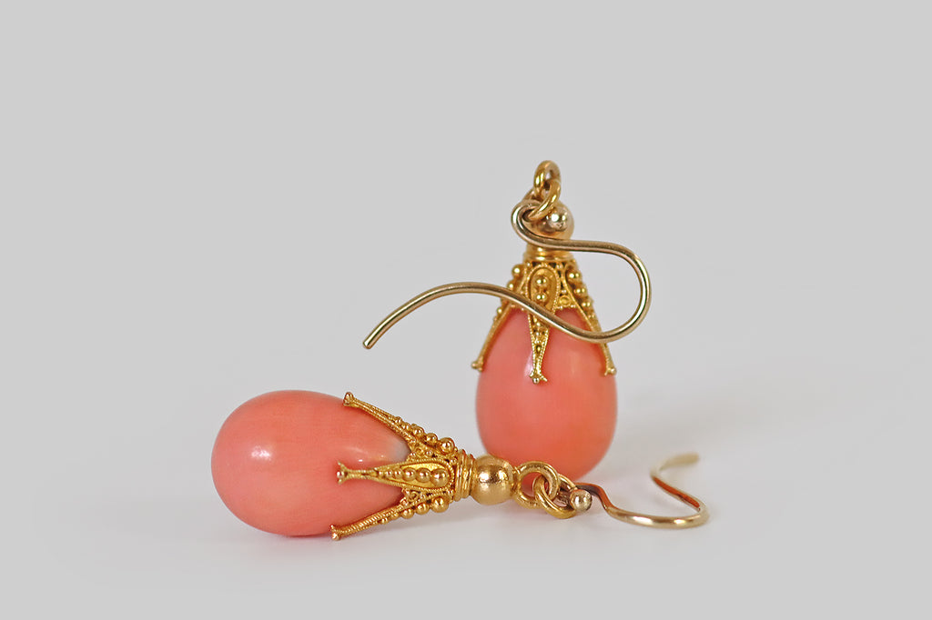 Poor Mouchette | Curated Antique Jewelry, Vintage Jewelry & Engagement Rings | Portland, Oregon | A pair of chubby, salmon-colored, natural coral teardrops, capped with ornate, five-claw mounts. These claws are extra-long and slender— they are decorated with fine twisted wirework and precisely-graduated balls of granulation. A gold ring connects these clawed toppers to a pair of handmade shepherd's hook ear wires.