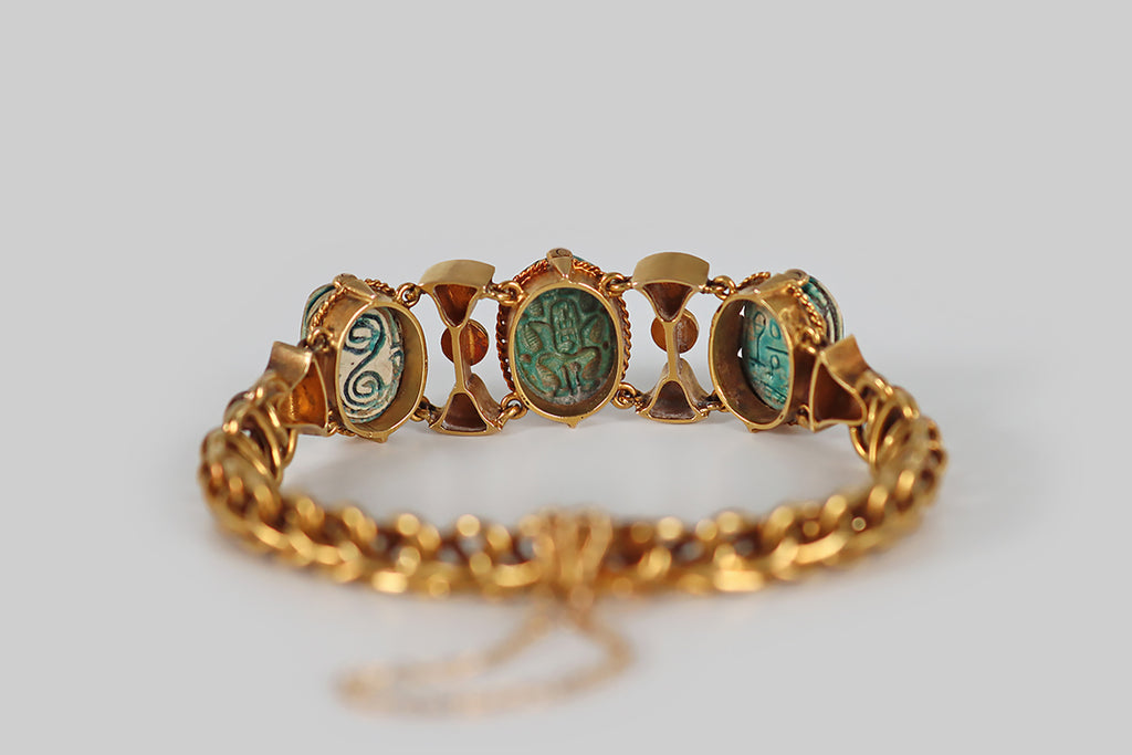 Antique Jewelry Portland, Vintage Jewelry Portland , Antique Engagement Rings | Poor Mouchette | A Victorian-era, Egyptian revival bracelet, modeled in 18k yellow gold, and set with a trio of ancient, glazed, faience/steatite scarabs. The body of this bracelet is an ornate handmade chain, comprised of curled links that move sinuously, giving the impression of vertebrae or scales. The bracelet's face features a series of cloisonné elements that act as spacers for the bracelet's three scarab