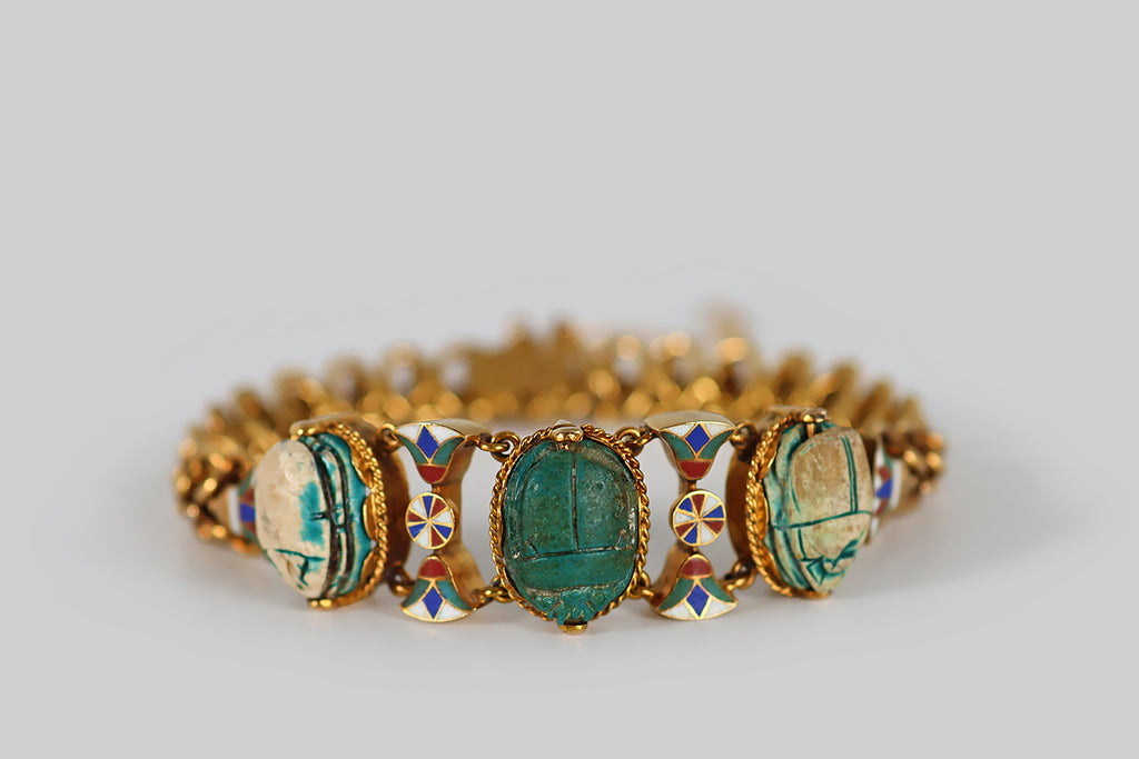 Antique Jewelry Portland, Vintage Jewelry Portland , Antique Engagement Rings | Poor Mouchette | A Victorian-era, Egyptian revival bracelet, modeled in 18k yellow gold, and set with a trio of ancient, glazed, faience/steatite scarabs. The body of this bracelet is an ornate handmade chain, comprised of curled links that move sinuously, giving the impression of vertebrae or scales. The bracelet's face features a series of cloisonné elements that act as spacers for the bracelet's three scarab 