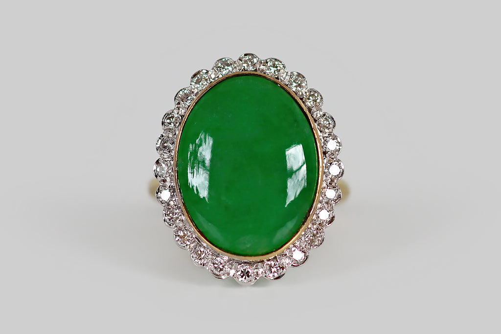 Antique Jewelry Portland, Vintage Jewelry Portland , Antique Engagement Rings | Poor Mouchette | A mid twentieth century cocktail ring, modeled in 14k white and yellow gold, whose primary gem is a large, natural, jadeite jade cabochon. This untreated, 'A jade' cabochon is held in a slim, yellow gold bezel, where it is surrounded by a bevy of sparkling, white, single cut diamonds. This petite diamond border has a charming, scalloped edge