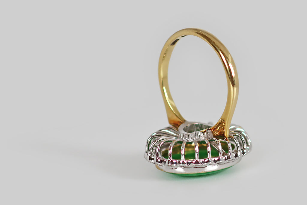 Antique Jewelry Portland, Vintage Jewelry Portland , Antique Engagement Rings | Poor Mouchette | A mid twentieth century cocktail ring, modeled in 14k white and yellow gold, whose primary gem is a large, natural, jadeite jade cabochon. This untreated, 'A jade' cabochon is held in a slim, yellow gold bezel, where it is surrounded by a bevy of sparkling, white, single cut diamonds. This petite diamond border has a charming, scalloped edge