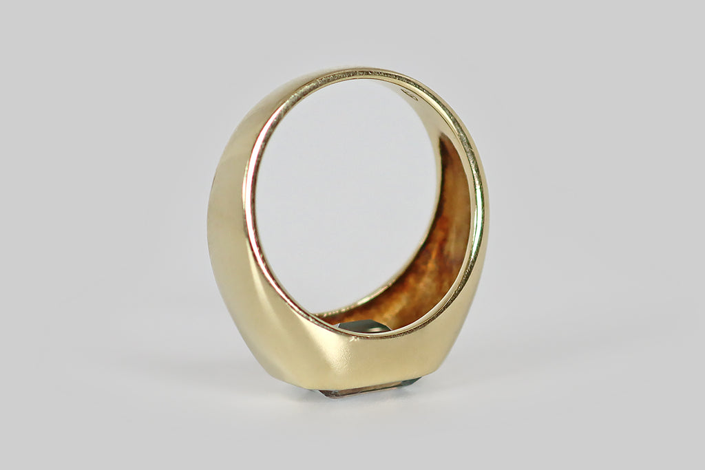Poor Mouchette | Curated Antique Jewelry, Vintage Jewelry & Engagement Rings | A very cool vintage ring, modeled in 14k yellow gold, whose gem is a large, step-cut aquamarine (about 2.2 carats). This emerald cut aquamarine is held in a burnished, low-profile bezel atop the ring's signet-style head. The ring's integral shank is wide at the shoulder, tapering gradually toward the base.