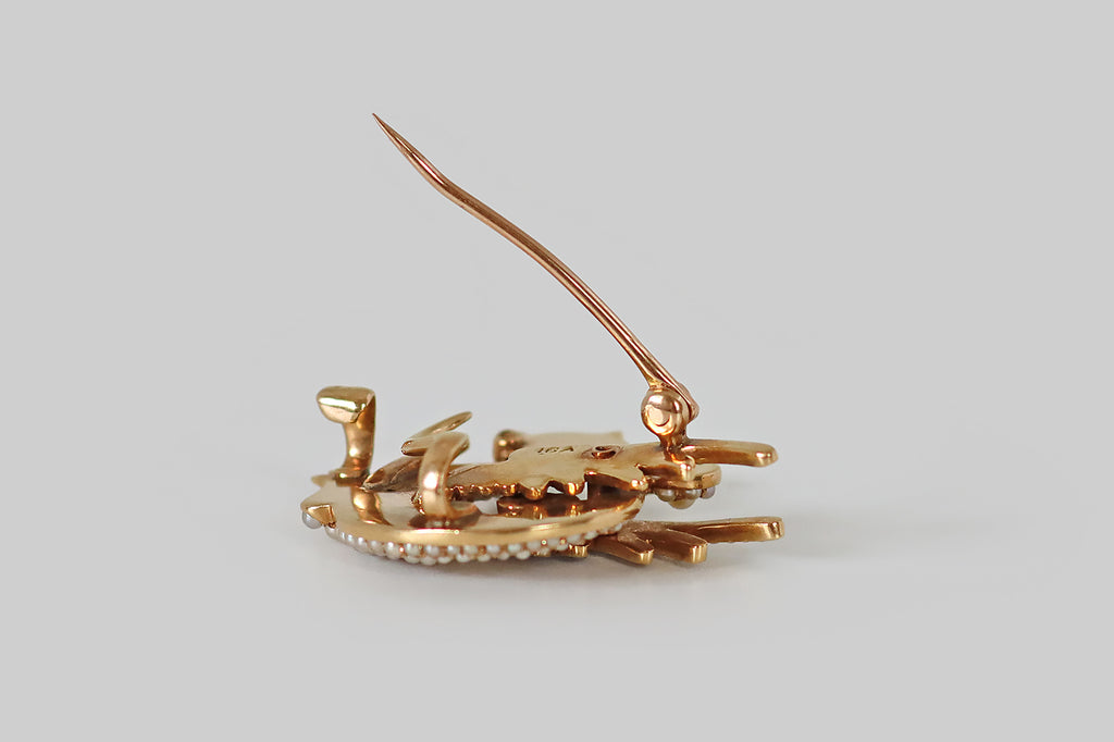 Antique Jewelry Portland, Vintage Jewelry Portland , Antique Engagement Rings | Poor Mouchette |An Art Nouveau era brooch, modeled as an adorable wyvern (dragon) in 14k yellow gold. Our beautiful beast is dimensional, highly stylized, and she is covered with a multitude of tiny natural pearls that represent her scales! She is winged, with two legs, a curling tail, and a vibrant green demantoid garnet eye. She hold an old European cut diamond in her mouth— a treasure that traditionally represents wisdom