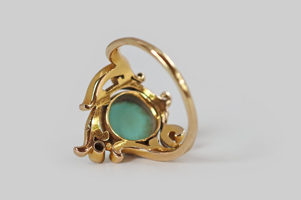 Poor Mouchette | Curated Antique Jewelry, Vintage Jewelry & Engagement Rings | Portland, Oregon | An Art Nouveau era ring, modeled in 14k bloomed yellow gold, whose primary gem is a large, robin's egg blue, Persian turquoise cabochon. This high-dome cab rests in six sets of triple-prongs, where curling, plume-like gold forms appear to bend and swirl around it. At the top of the ring face, and slightly off center, a bezel-set old mine cut diamond floats between two of these plumes.
