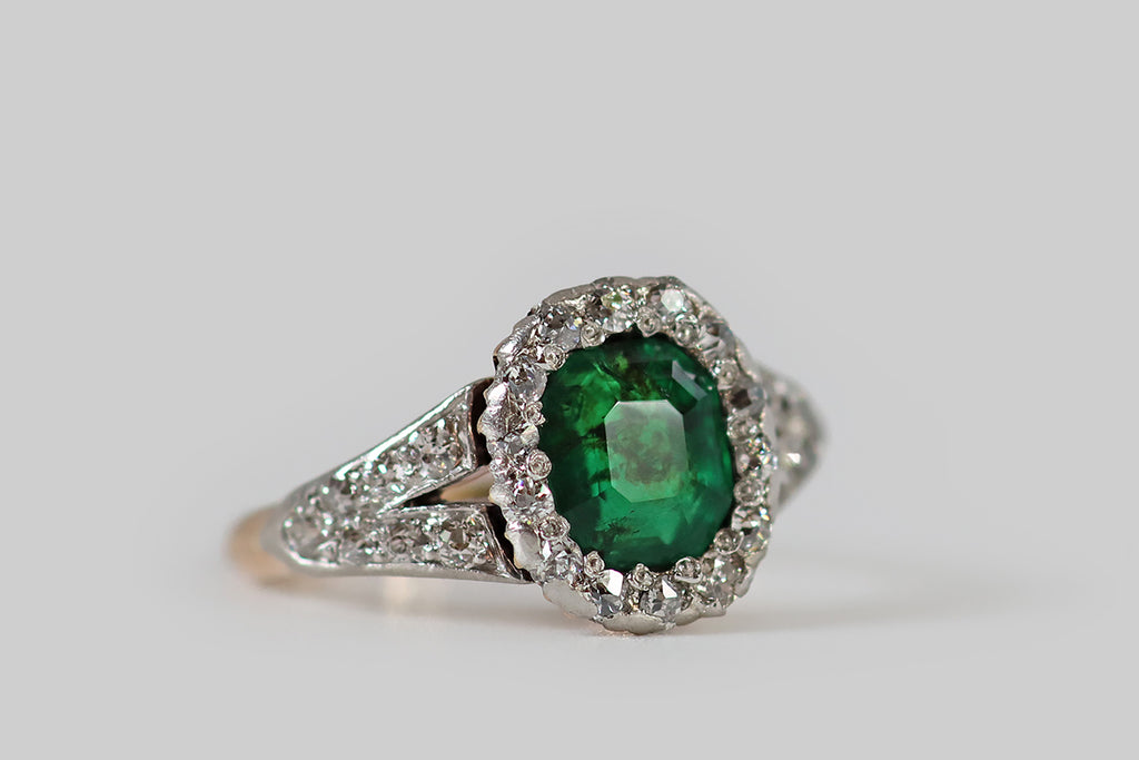 Poor Mouchette | Curated Antique Jewelry, Vintage Jewelry & Engagement Rings | Portland, Oregon | A striking Belle Époque era ring, modeled in 14k rosy yellow gold and platinum, whose primary gem is a natural step-cut emerald, with an especially intense, deep green color! This emerald is faceted in the old style, with a small, low, eight-sided table, and stepped facets that extend from each of its sides.