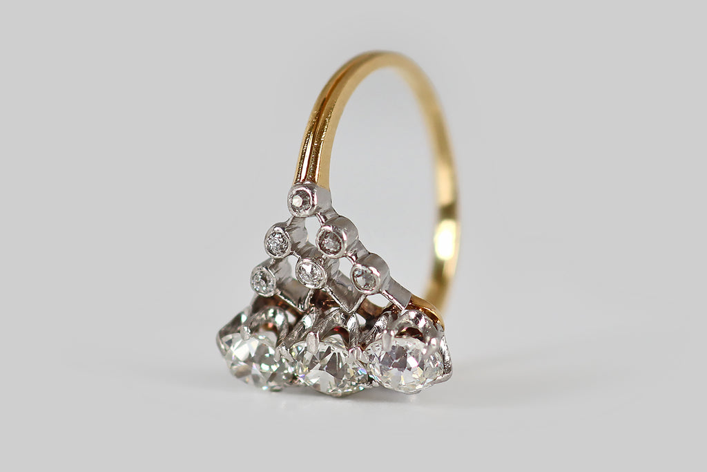 Antique Jewelry Portland, Vintage Jewelry Portland , Antique Engagement Rings | Poor Mouchette | A belle epoque era engagement ring, modeled in 18k yellow gold and platinum, whose face is an openwork, diamond-studded lattice, with three old European cut diamonds resting at center. These primary diamonds (G/H, VS) are arranged in a vertical row, where they are each held in six claw-like prongs. The lattice-work they sit atop is dotted with 12 additional old cut diamonds, that are seated in small
