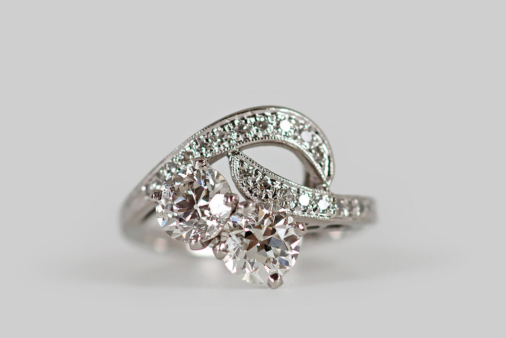 Poor Mouchette | Curated Antique Jewelry, Vintage Jewelry & Engagement Rings | An elegant, Retro-era, toi et moi engagement ring, modeled in white gold (18k&14k), by the well-known Canadian jewelry house, Birks. This ring features a matched pair of very sparkly, white, old European cut diamonds (.96 carats, and .94 carats). These old hand-cut diamonds are held in crown-like, four-prong mounts, and are tucked up against a pair of long, curving forms that complete the ring face.