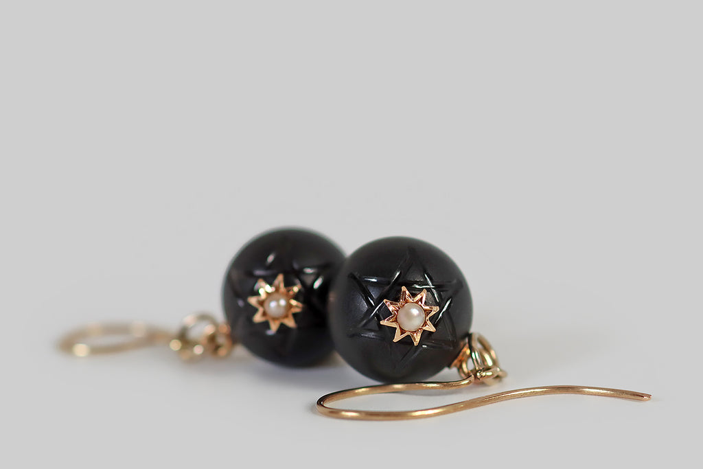 Antique Jewelry Portland, Vintage Jewelry Portland , Antique Engagement Rings | Poor Mouchette | A very cool pair of Victorian era earrings whose dangling black-onyx orbs are carved with the Star of David. These black orbs have a matte finish, so the shining lines of carved six-pointed star stand out, subtly, from the rest of the surface. An eight-pointed gold star rests at the center of each larger, star-shaped symbol, and a creamy seed pearl is set at the center of each smaller star.