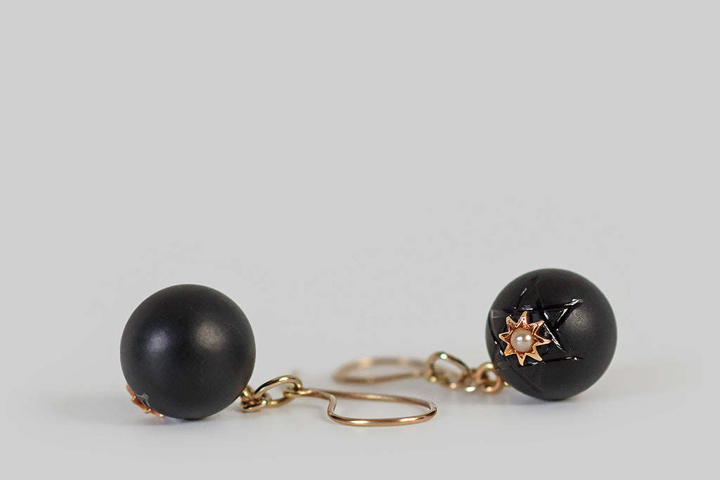 Antique Jewelry Portland, Vintage Jewelry Portland , Antique Engagement Rings | Poor Mouchette | A very cool pair of Victorian era earrings whose dangling black-onyx orbs are carved with the Star of David. These black orbs have a matte finish, so the shining lines of carved six-pointed star stand out, subtly, from the rest of the surface. An eight-pointed gold star rests at the center of each larger, star-shaped symbol, and a creamy seed pearl is set at the center of each smaller star.