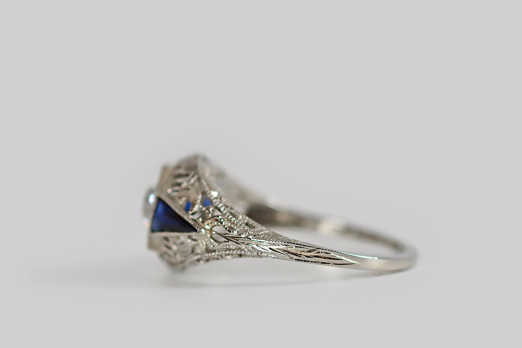 Antique Jewelry Portland, Vintage Jewelry Portland , Antique Engagement Rings | Poor Mouchette | A classic, Art Deco era, filigree engagement ring, modeled in 18k white gold and set with a chunky .52 carat old European cut diamond (F/G, SI1). This sparkling, white diamond is bead-set into an octagonal seat at the center of the ring face, which is low-profile and softly domed. It is flanked by a pair of deep blue, elongated, pennant-shaped, created sapphires.