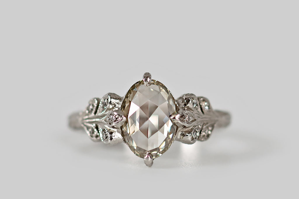 Poor Mouchette | Curated Antique Jewelry, Vintage Jewelry & Engagement Rings | A one-of-a-kind, low-profile engagement ring, designed by Cathy Waterman and modeled in platinum, whose primary gem is a 1.56 carat, oval, rose cut diamond. This bright, warm-tone diamond is beautifully cut and exceptionally clean (K/L, VS1). It is held in claw-like prongs, at its north and south points