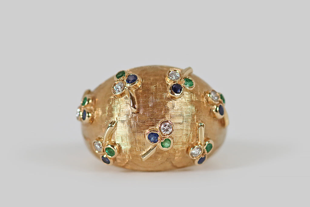 Poor Mouchette | Curated Antique Jewelry, Vintage Jewelry & Engagement Rings | Portland, Oregon | A whimsical, mid-twentieth-century, domed, bombe ring, modeled in 14k yellow gold, whose plump form is decorated with applied, gem-set clovers! These seven three-leaf clovers are strewn across the ring face in a charming, naturalistic manner, as if they were tossed into the air, and landed (here and there) on its textured surface.