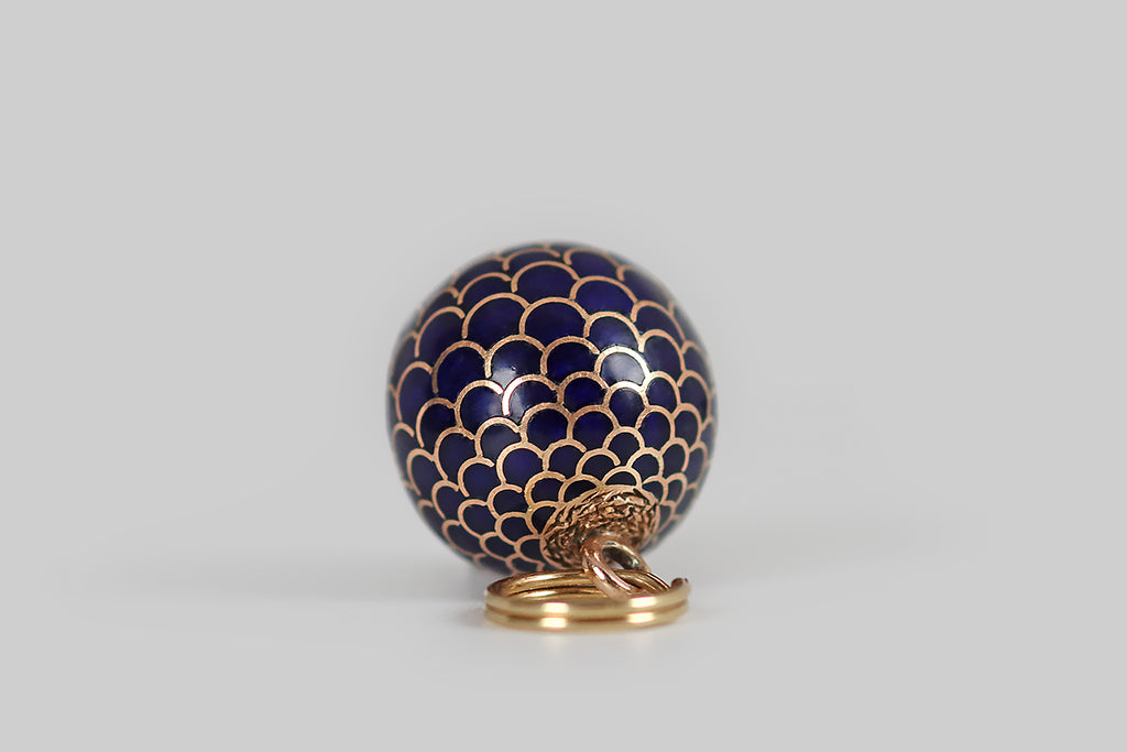 Antique Jewelry Portland, Vintage Jewelry Portland , Antique Engagement Rings | Poor Mouchette | A beautiful, early 20th century charm, modeled in rosy 14k yellow gold and decorated with glassy cobalt blue enamel. This orb-shaped charm has an all-over pattern of scales (or feathers) that are largest at its center— the pattern of scales tightens at the orb's poles. This scaled look