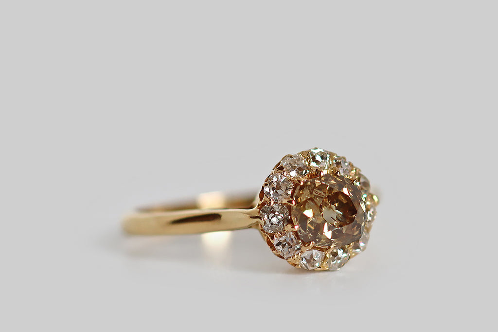 Poor Mouchette | Curated Antique Jewelry, Vintage Jewelry & Engagement Rings | A striking Victorian-era halo ring, modeled in 18k yellow gold, whose primary gem is a fancy-brown old mine cut diamond (.69 carats). This diamond is a rich, neutral, golden-brown color that might be described as whiskey, or cognac. It is chunky, with a small, irregular table and steep crown facets