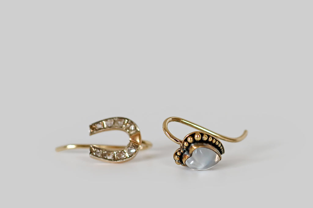 Antique Jewelry Portland, Vintage Jewelry Portland , Antique Engagement Rings | Poor Mouchette | A dainty pair of mismatched drop earrings whose subjects, a lucky horseshoe and a moonstone heart, rest on the wearer's earlobe. The tiny horseshoe, here, is faced with platinum and is set with eight, glinting rose cut diamonds.