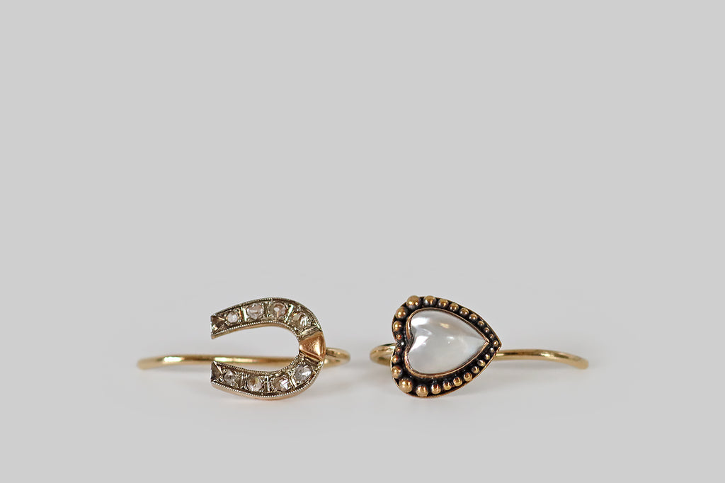 Antique Jewelry Portland, Vintage Jewelry Portland , Antique Engagement Rings | Poor Mouchette | A dainty pair of mismatched drop earrings whose subjects, a lucky horseshoe and a moonstone heart, rest on the wearer's earlobe. The tiny horseshoe, here, is faced with platinum and is set with eight, glinting rose cut diamonds.